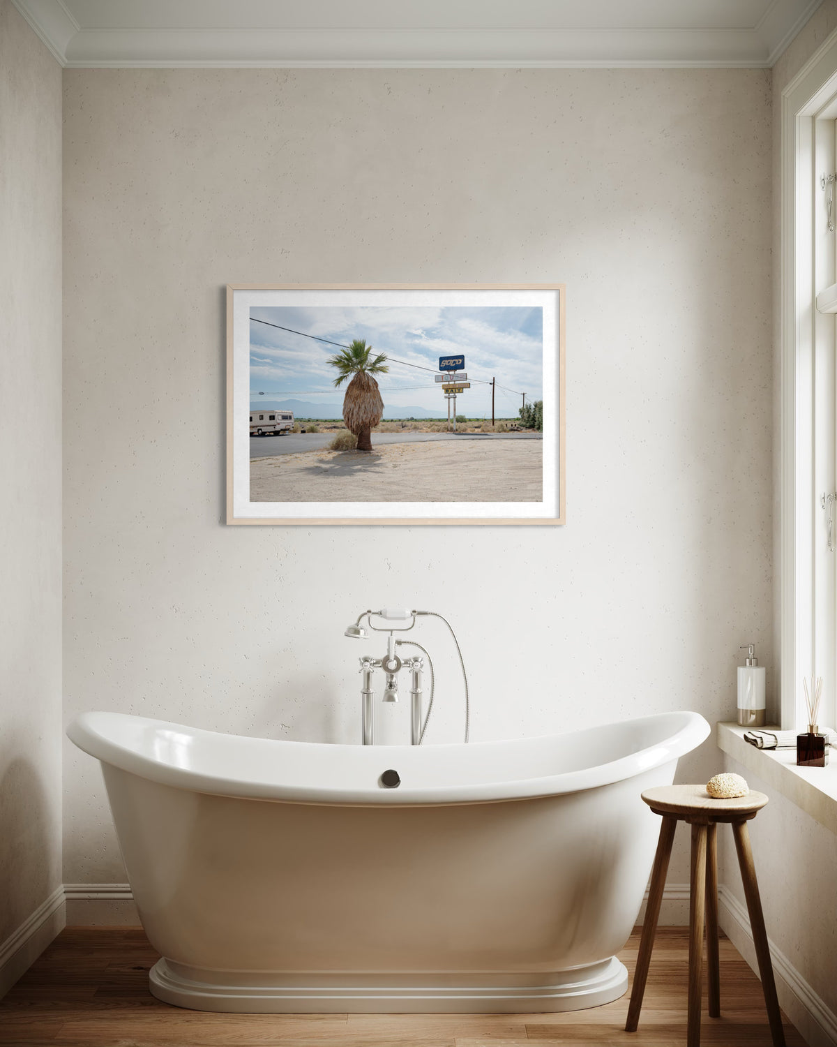 Framed “Palm Desert Roadside” photograph of a desert road hanging above a white tub in a modern bathroom.