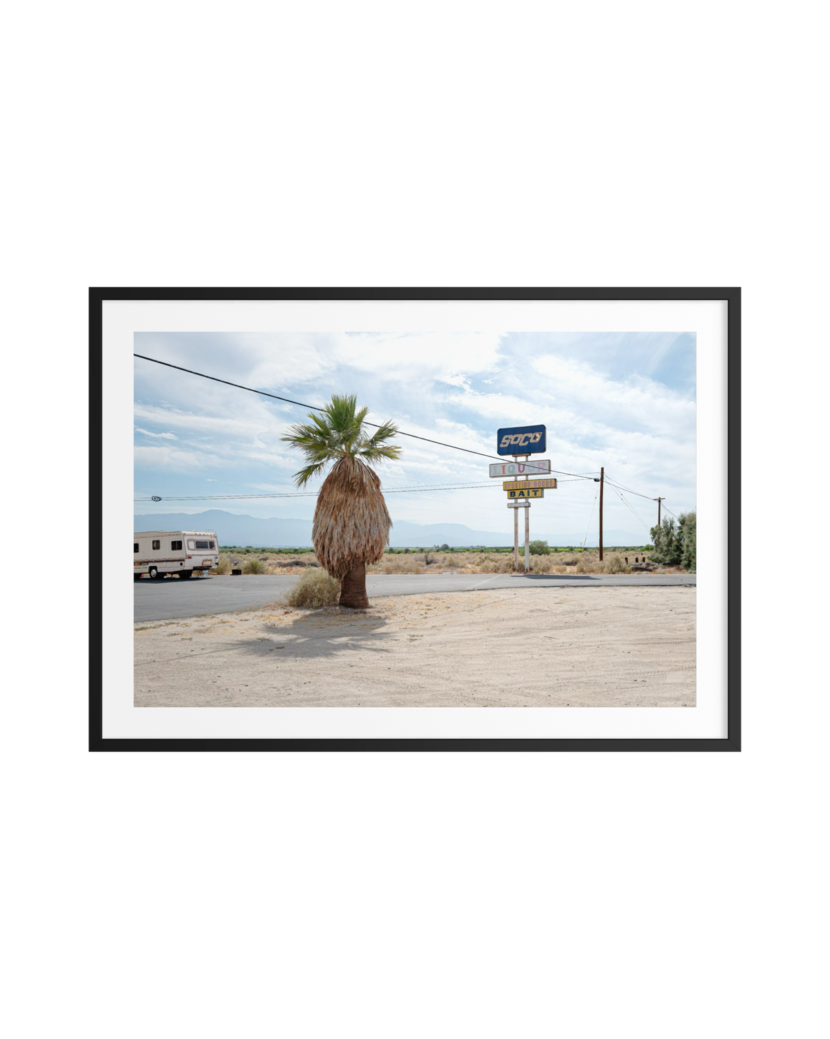 Lone palm tree, RV, and motel sign along a Palm Desert road under a vibrant sunset sky.