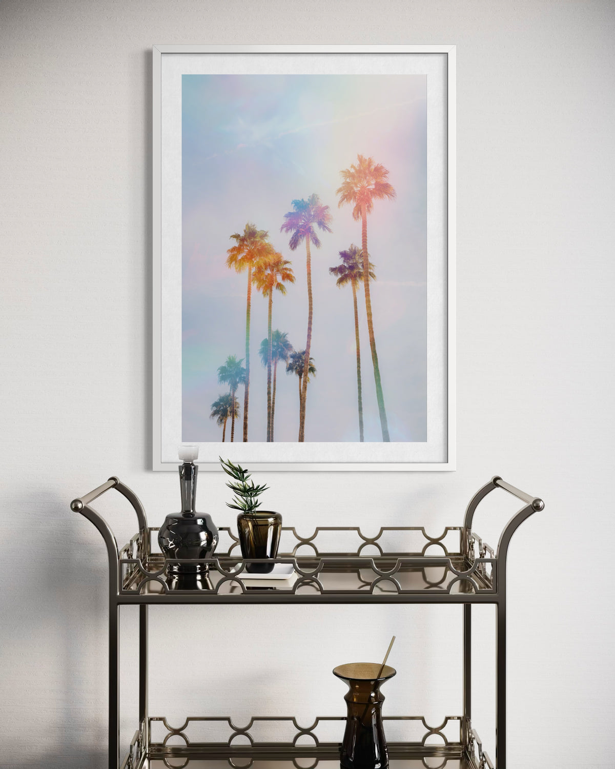 Framed photograph of palm trees in Palm Springs above a gold bar cart with plants and glassware.