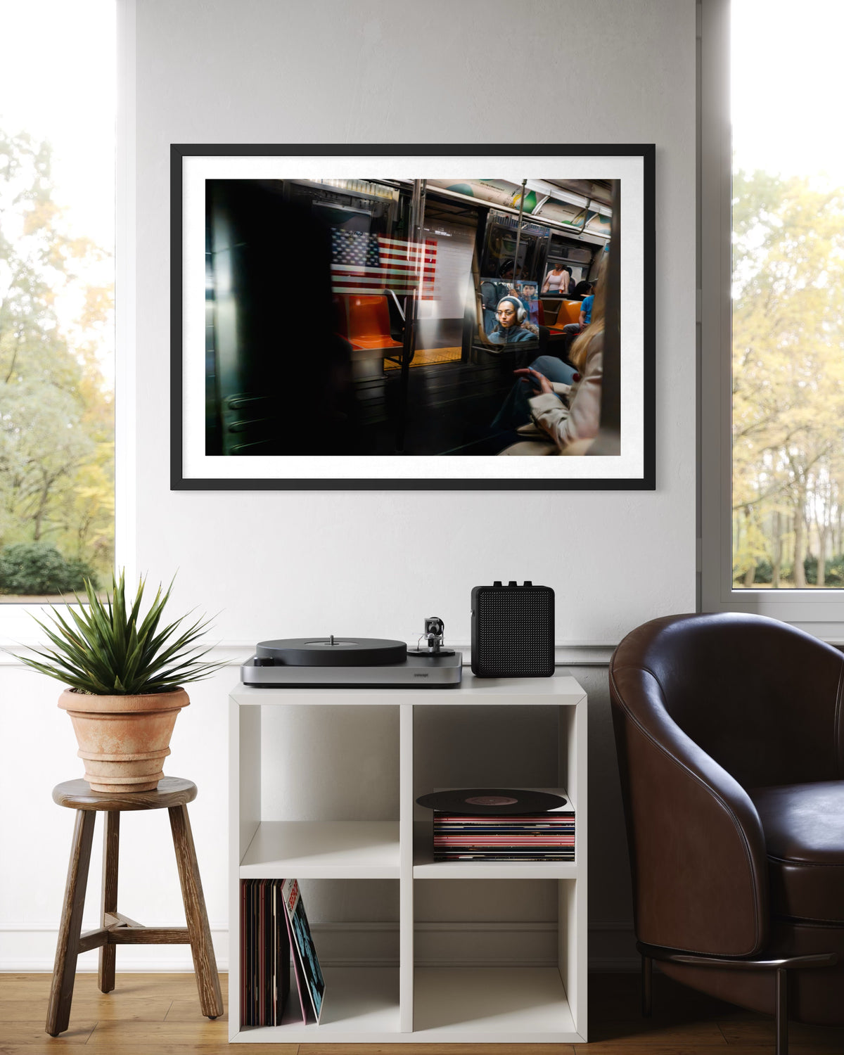 Black and white photo of a train passing in New York City, shown framed above a record player near a window.
