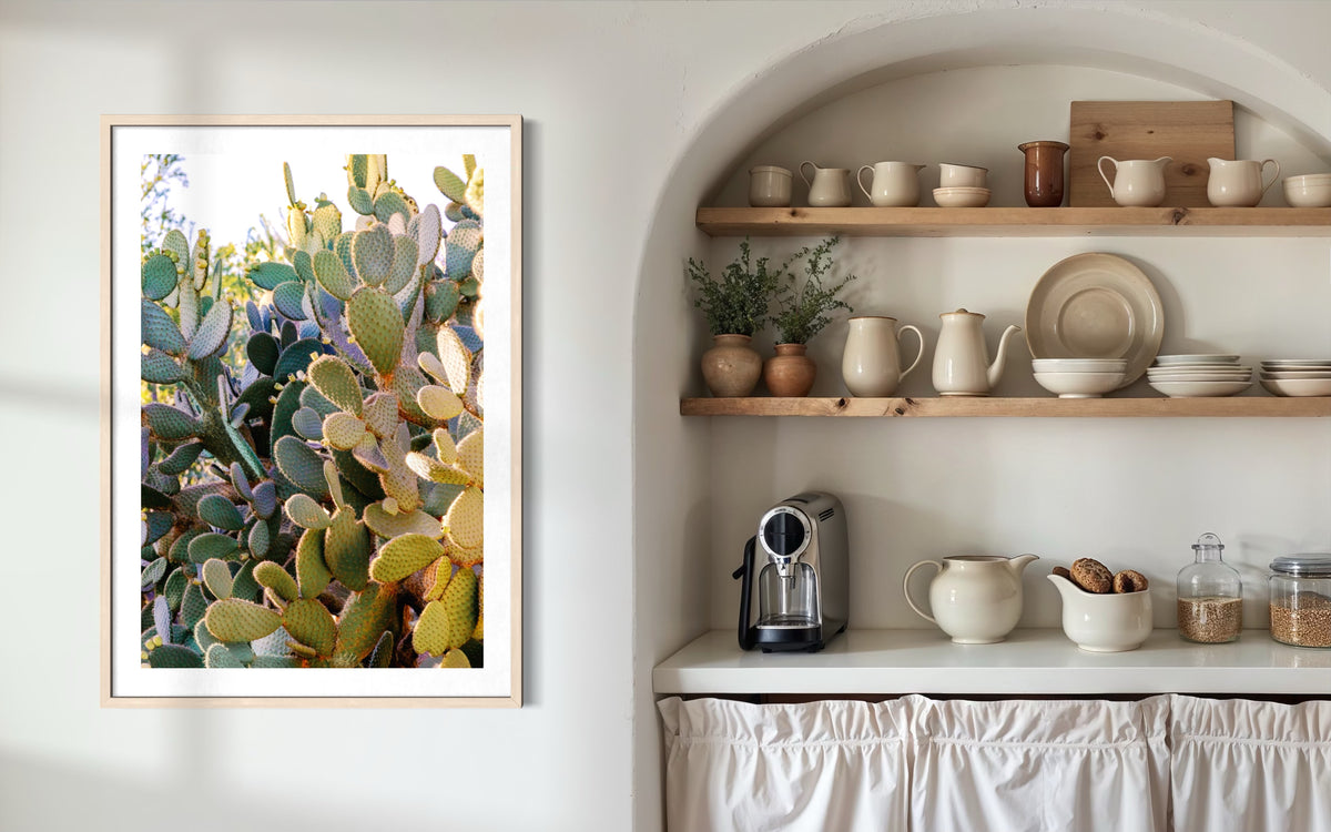 Neutral kitchen shelves with dishes, blue-green sage accents, Prickly Pear art, and espresso machine on counter.