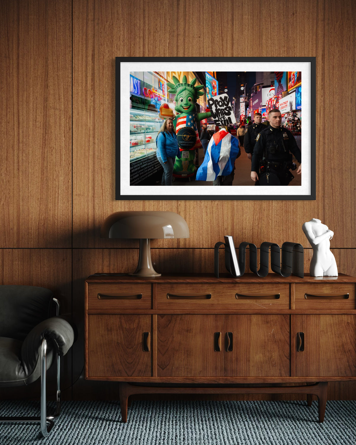 Framed “Proxy Wars Are Evil” print on wood-paneled wall above a mid-century credenza and lamp in a room setting.