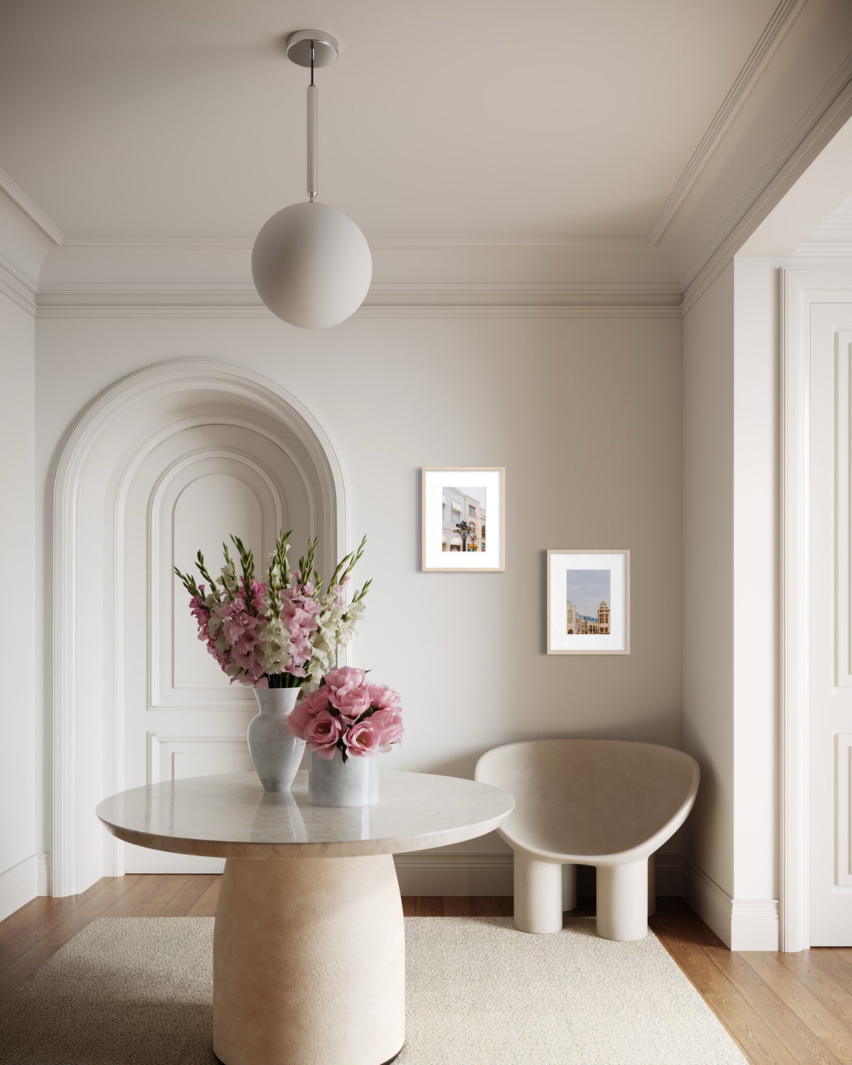 Round marble table with pink flowers and cream chair in a bright Beverly Hills entryway with an arched doorway.