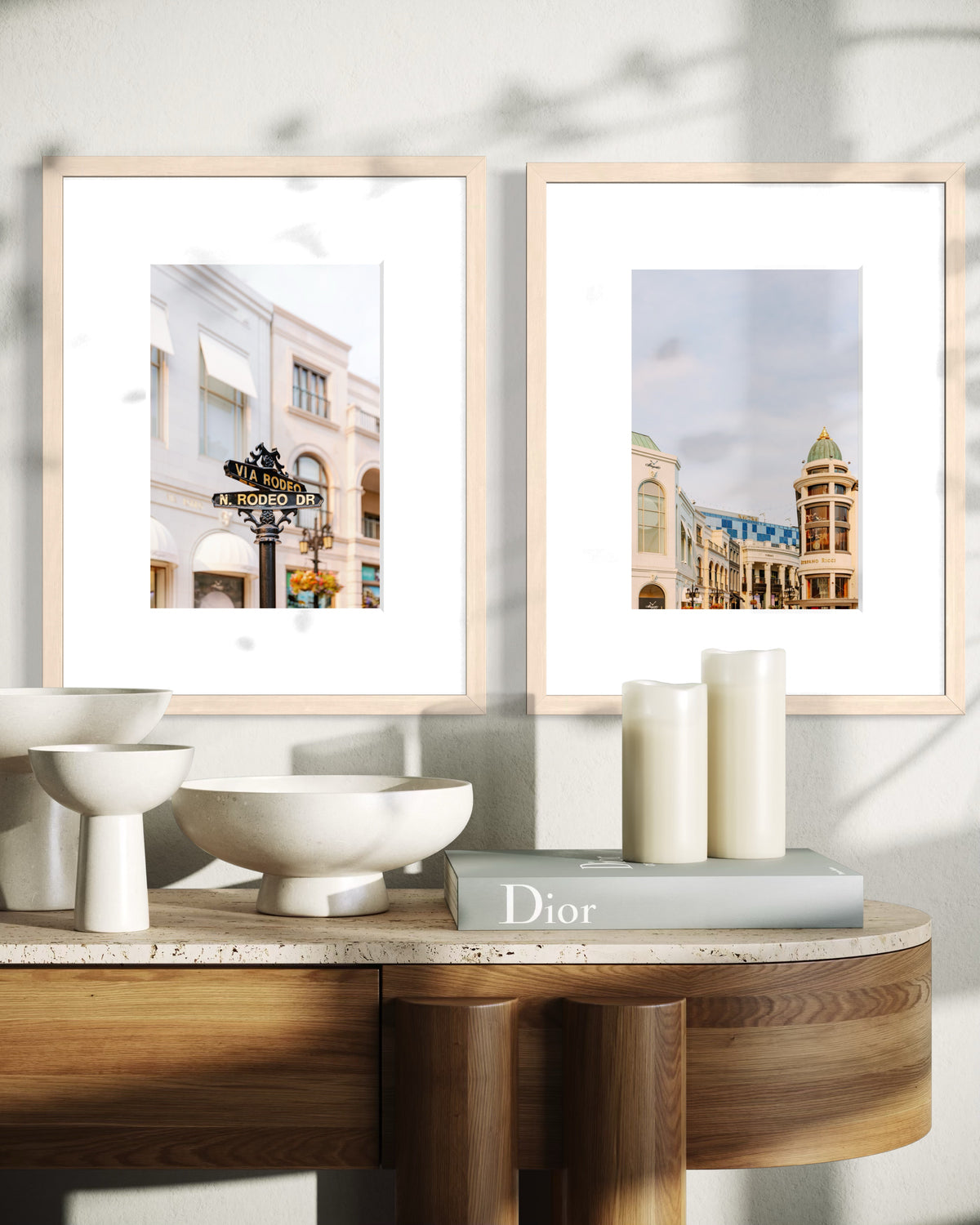 Framed Rodeo Drive photograph above a wooden table with white decor, candles, and a Dior book.
