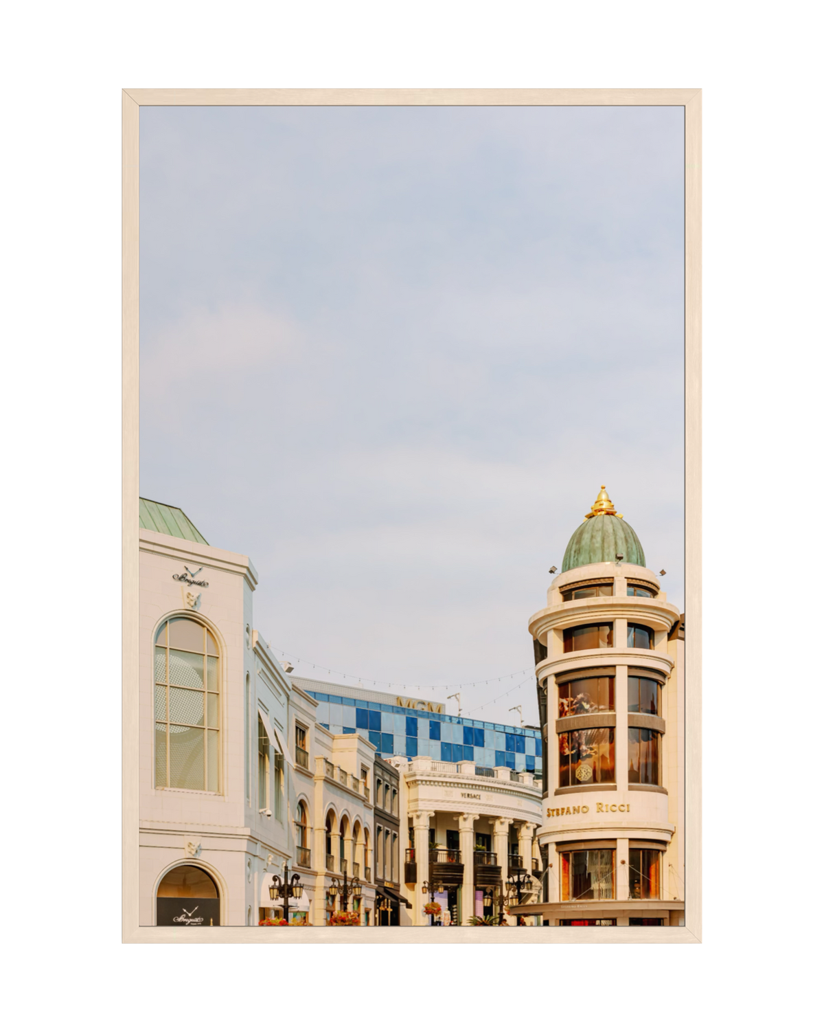 Shops along Rodeo Drive in Beverly Hills with a green-domed building and partly cloudy sky.