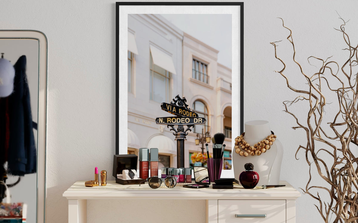 Makeup, jewelry, and a framed Rodeo Drive sign displayed on a dresser in Beverly Hills.
