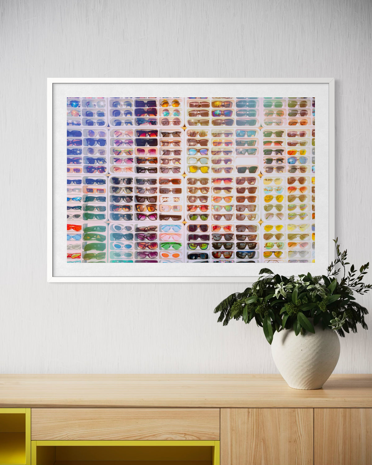Framed Shades of Summer print displayed above a wooden shelf with a potted green plant.