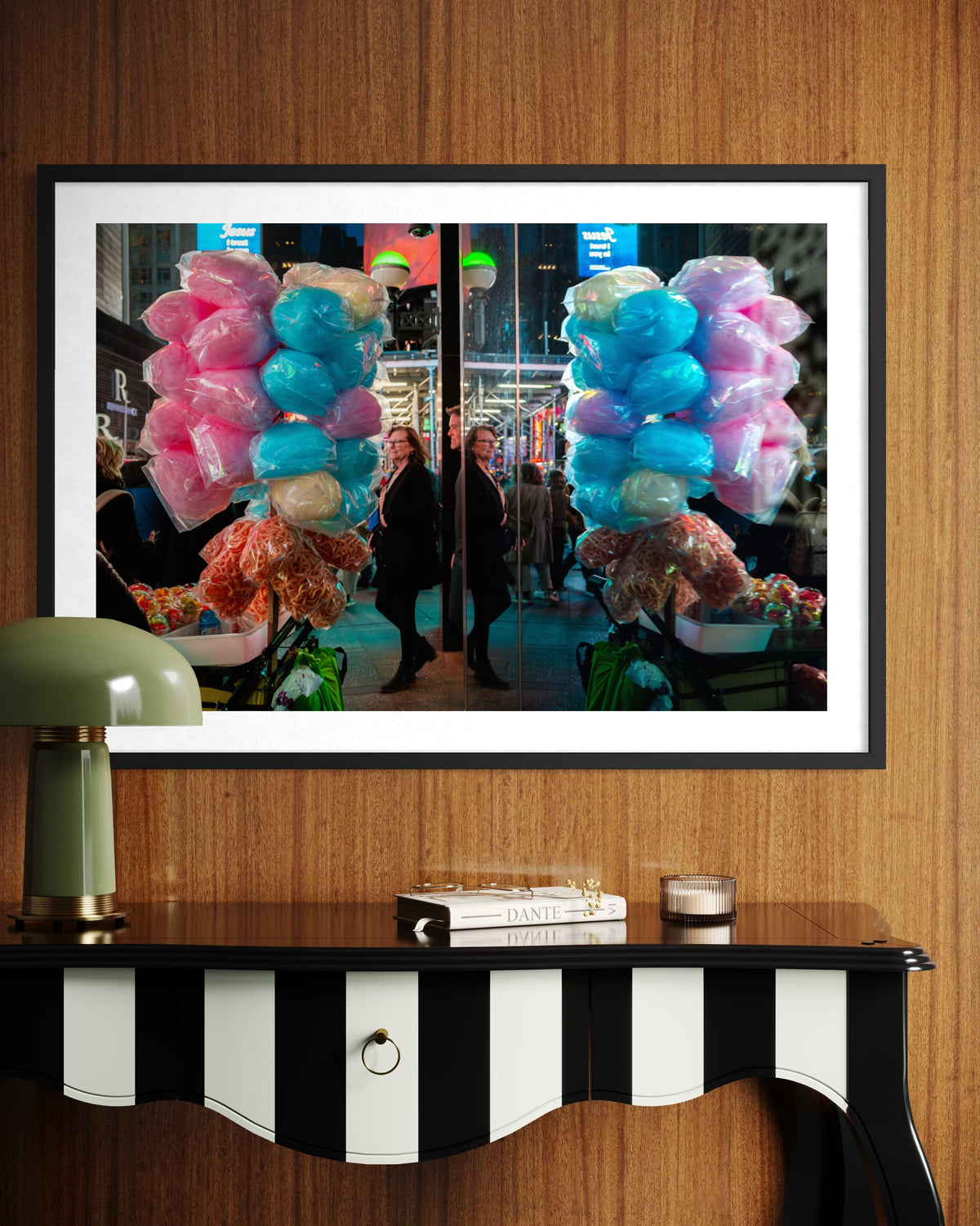 “Sweet Reflections” street photo print of an urban scene, framed and hanging above a striped table, books, and green lamp.
