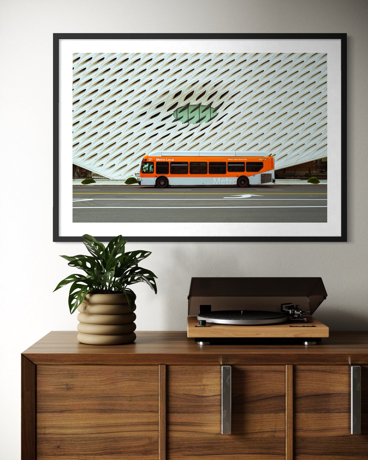 Framed print of The Broad museum in downtown Los Angeles displayed above a record player and potted plant.