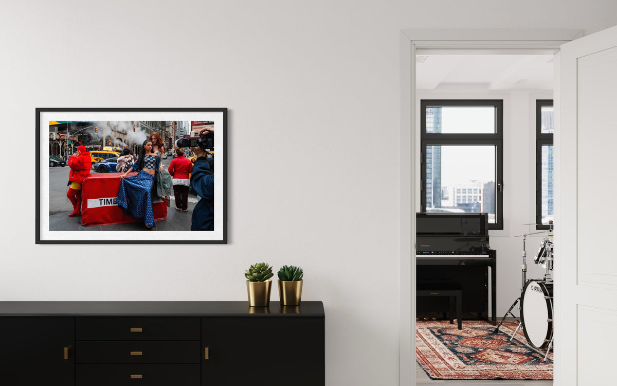Times Square street scene in New York City, photograph displayed above a black cabinet; doorway reveals drums.