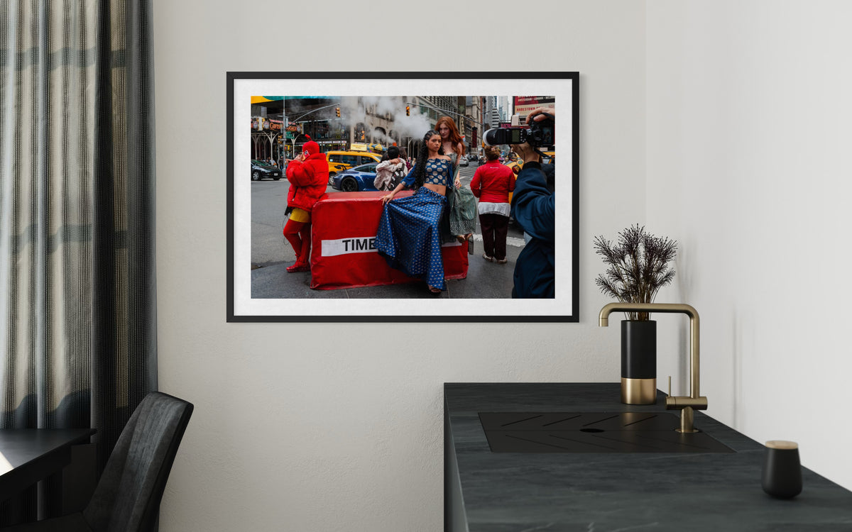 Black-and-white Times Square street photo hanging on a white wall above a dark counter and modern decor.