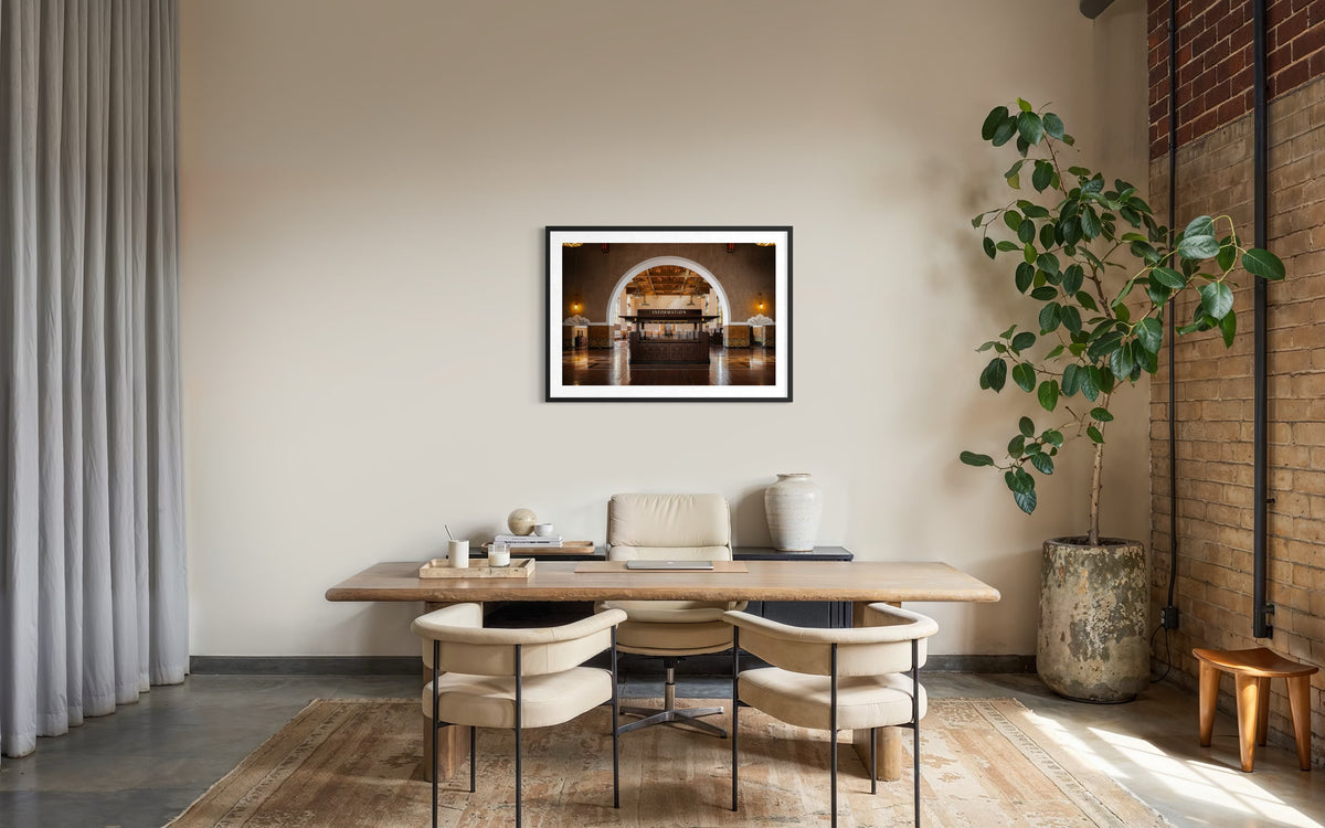 Wooden desk and two chairs in a minimalist office, Union Station Information art on beige wall, Los Angeles.