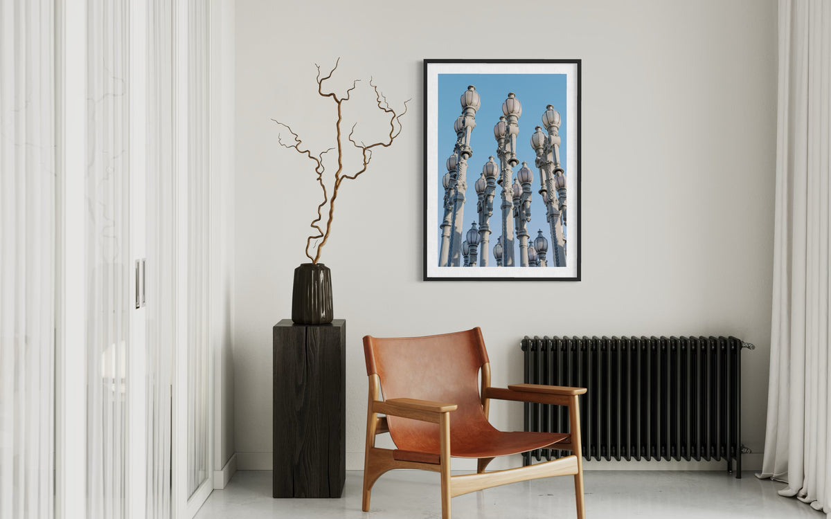 Framed photograph of Los Angeles’ Urban Light street lamps on a wall above a leather chair and vase.