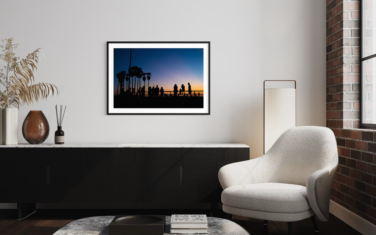 Venice Beach Summer Night“ framed print hangs above a black cabinet with white chair, lamp, and vases in room mockup.