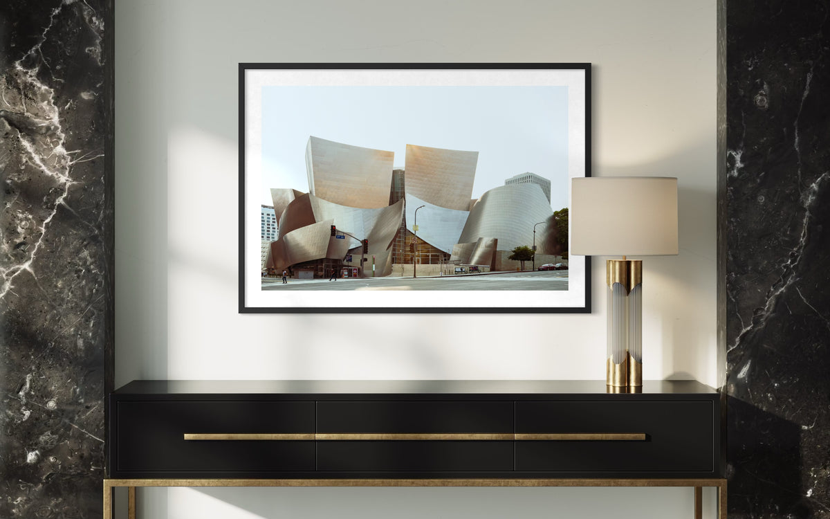 Walt Disney Concert Hall in Los Angeles pictured above a black console and lamp on a marble-accented wall.