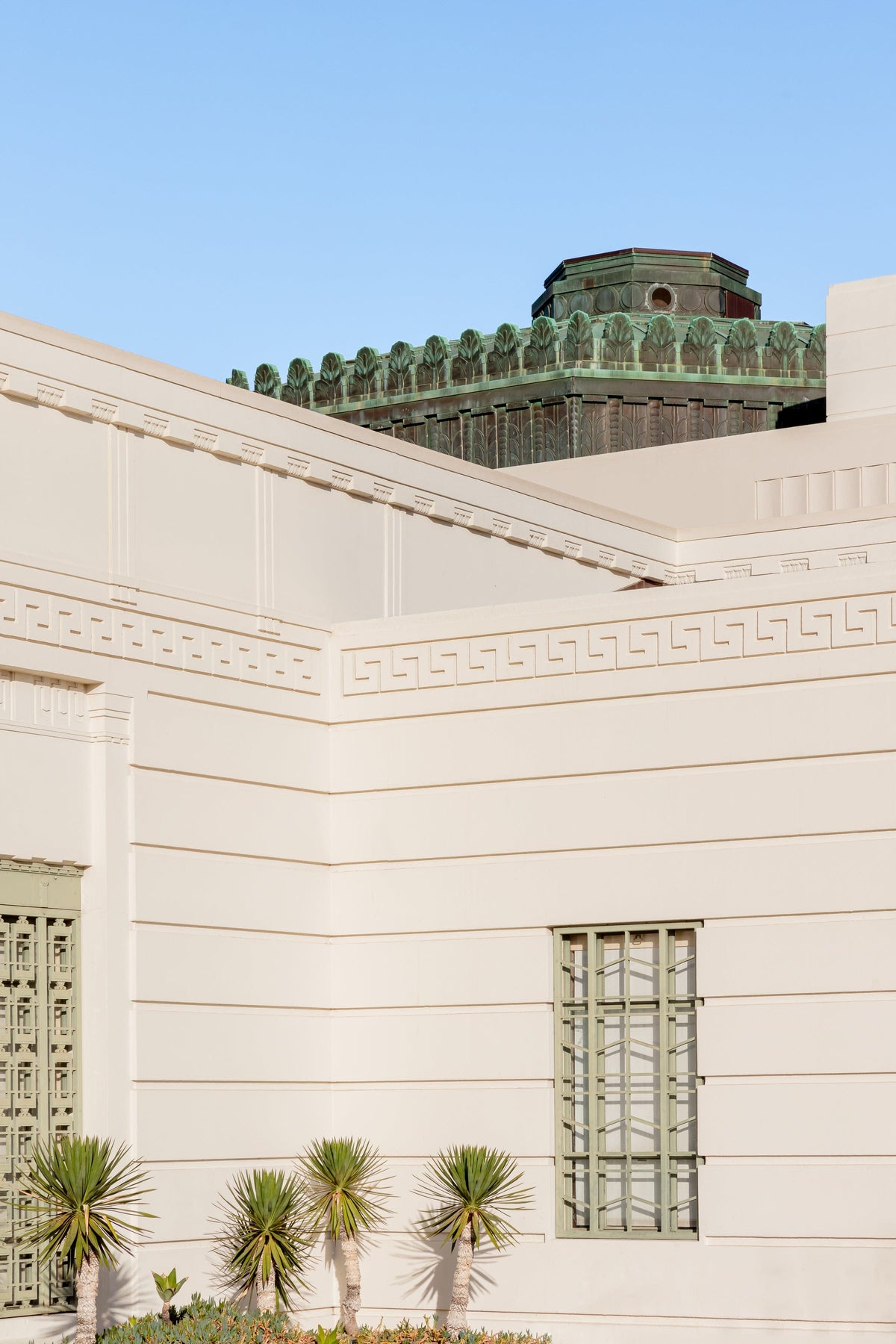 Griffith Observatory’s cream Art Deco façade and palm trees beneath a blue sky in Los Angeles, California.