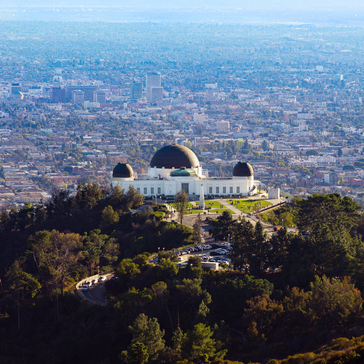 Griffith Observatory sits on a hill overlooking Los Angeles with the city skyline visible in the background.